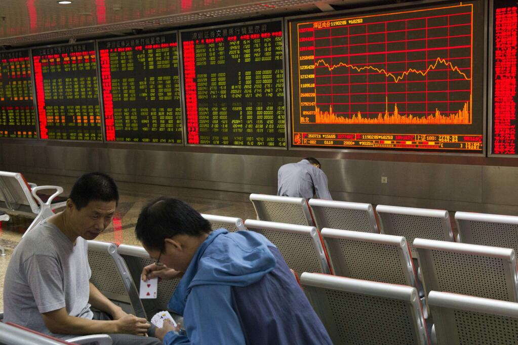 Investors play a card game near electronic boards displaying stock prices in Beijing, Friday, Aug. 21, 2015. Asian stocks fell further Friday after a survey showed Chinese manufacturing weakened this month. (AP Photo/Ng Han Guan)