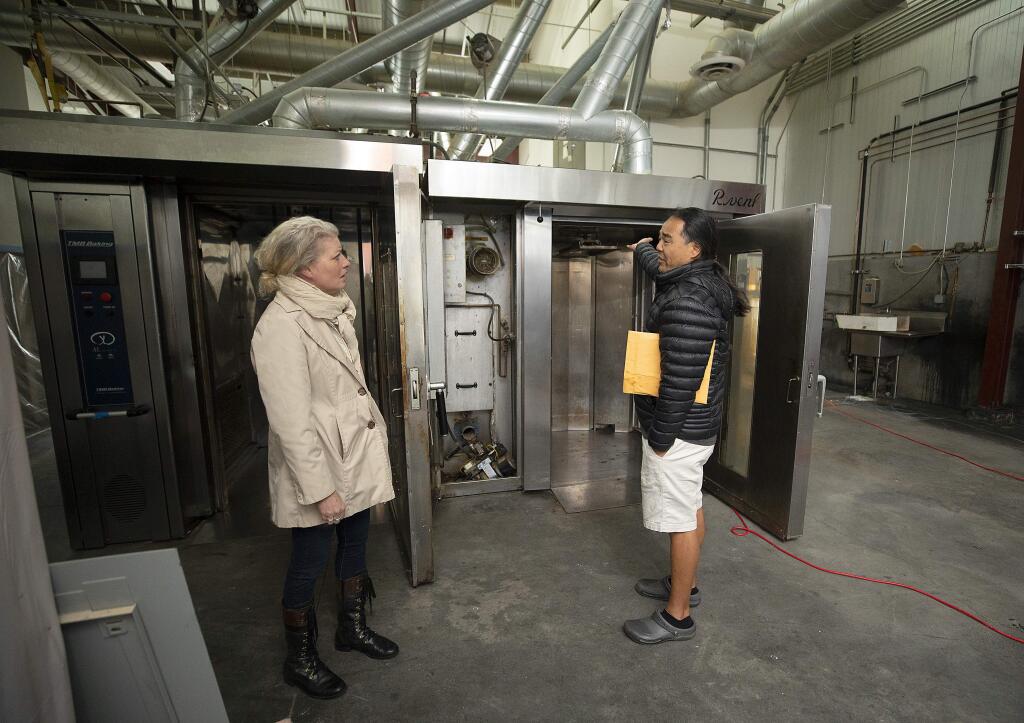 Village Bakery owner Patrick Lum and manager Lisa Schroeder check out two of the four bread and pastry ovens damaged by flood waters in Sebastopol's Barlow business district. Lum hopes to fix the ovens and open the production facility that also supplies their Santa Rosa store. (photo by John Burgess/The Press Democrat)