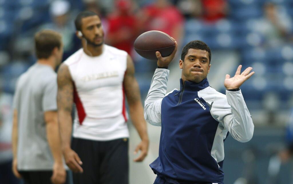Seahawks quarterback Russell Wilson, right, passes during warmups as Colin Kaepernick before the 49ers-Seahawks game, Sept. 15, 2013, in Seattle. (John Froschauer / Associated Press)