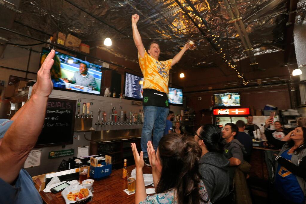 Bar owner Kevin Sprenger stands atop his bar singing, 'We are the Champions,' as he and other Warriors fans celebrate the team's NBA championship victory over the Cleveland Cavaliers at Sprenger's Taproom in Santa Rosa, California, on Monday, June 12, 2017. (Alvin Jornada / The Press Democrat)