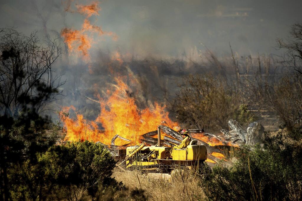 A firefighter creates a fire break as the Maria Fire approaches in Santa Paula, Calif., on Friday, Nov. 1, 2019. According to Ventura County Fire Department, the blaze has scorched more than 8,000 acres and destroyed at least two structures. (AP Photo/Noah Berger)