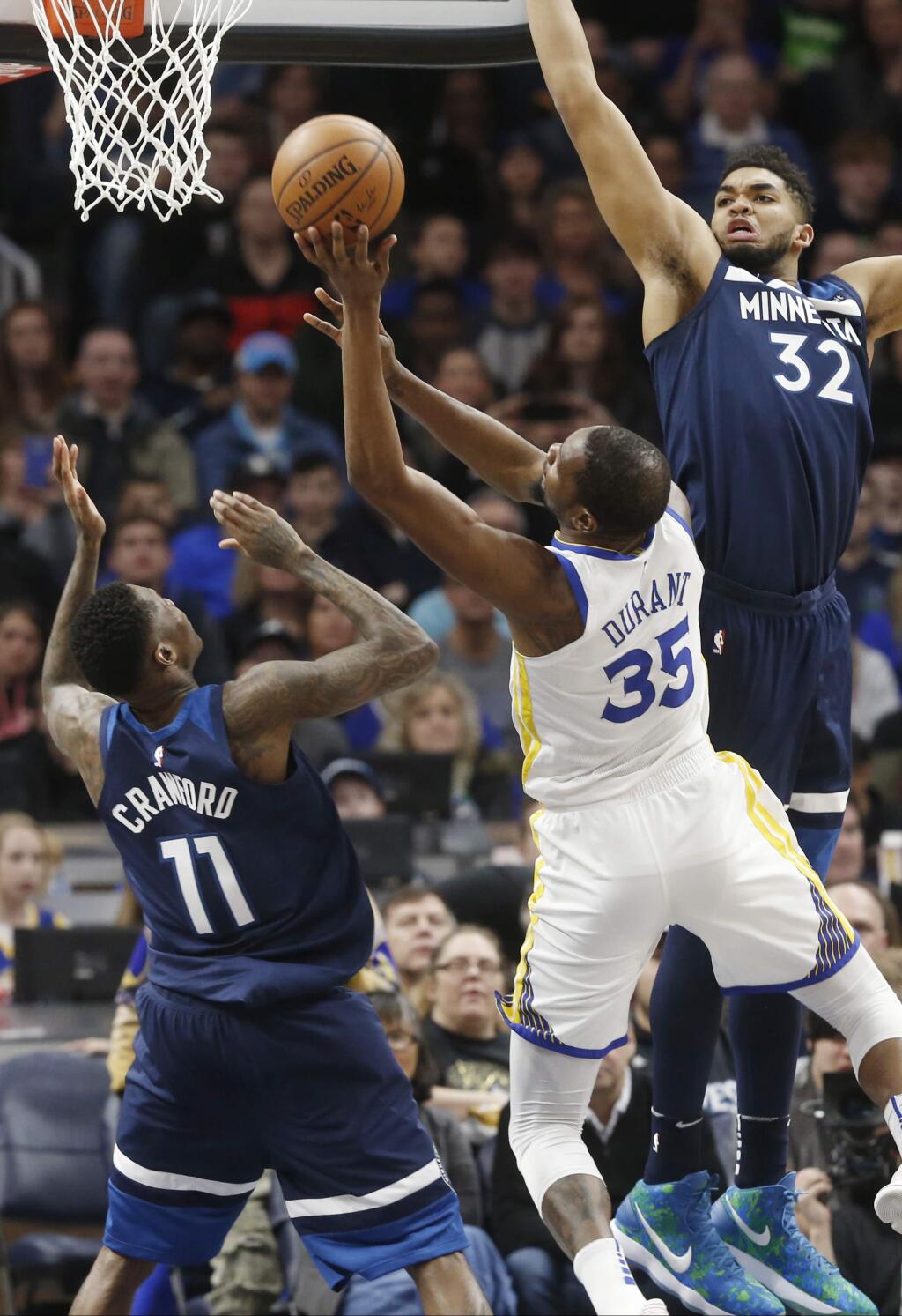 Golden State Warriors' Kevin Durant, center, shoots between Minnesota Timberwolves' Jamal Crawford, left, and Karl-Anthony Towns in the first half of an NBA basketball game Sunday, March 11, 2018, in Minneapolis. (AP Photo/Jim Mone)