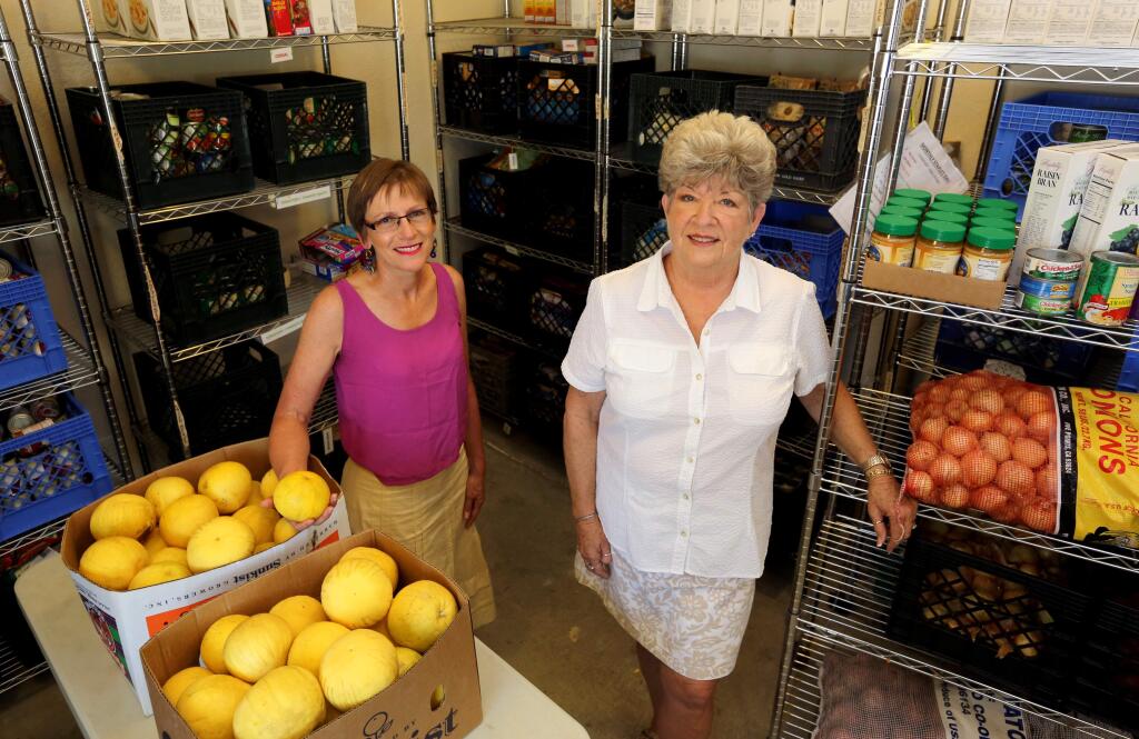 PHOTO: 1 BY CRISTA JEREMIASON/ THE PRESS DEMOCRAT -Jean Herschede, left, and MJ Dellaquila, co-directors of the “Christmas in June” event, stand in the food storage area of the Cloverdale Food Pantry.