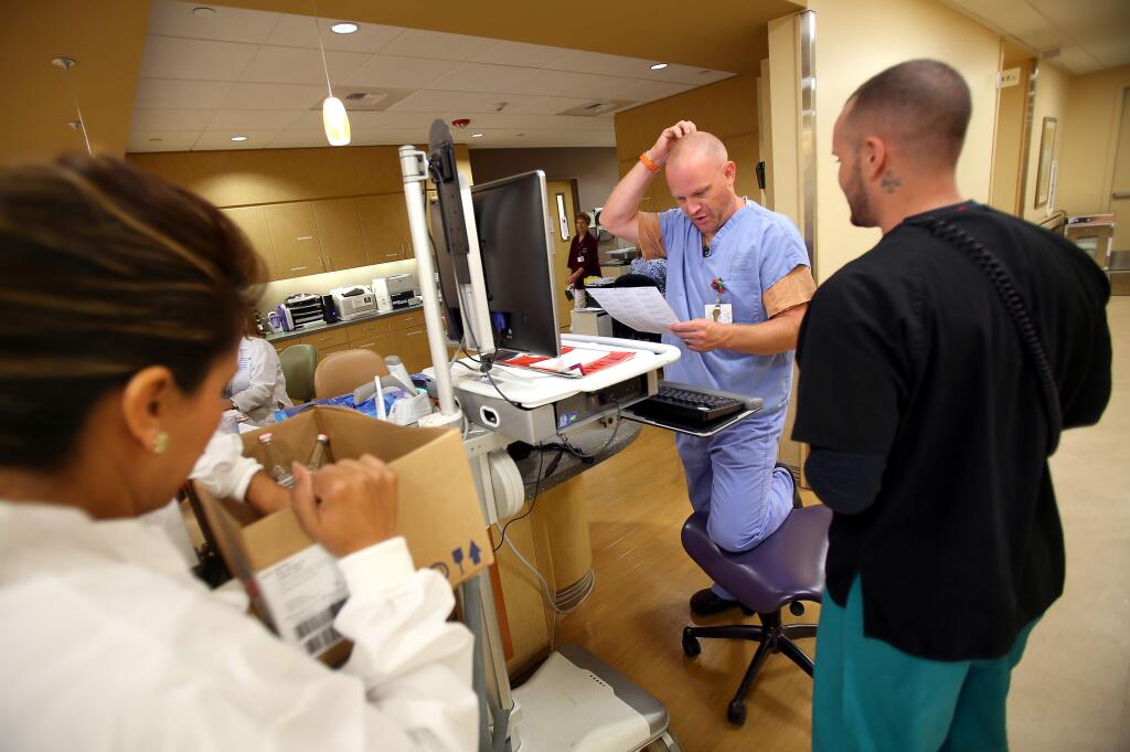 Registered nurse Eric Cartner, left, and emergency room technician Justin Irace work at a nurses station in the Santa Rosa Memorial Hospital emergency room, in Santa Rosa on Monday, August 4, 2014. (Christopher Chung/ The Press Democrat)