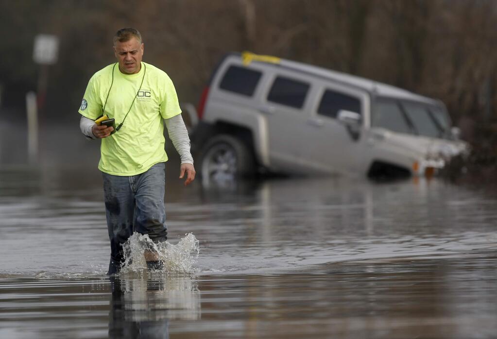 Tom Sandoval walks away from his flooded out Hummer on Sanford Rd after retrieving some personal effects from the vehicle on Friday, January 13, 2017. (BETH SCHLANKER/ The Press Democrat)