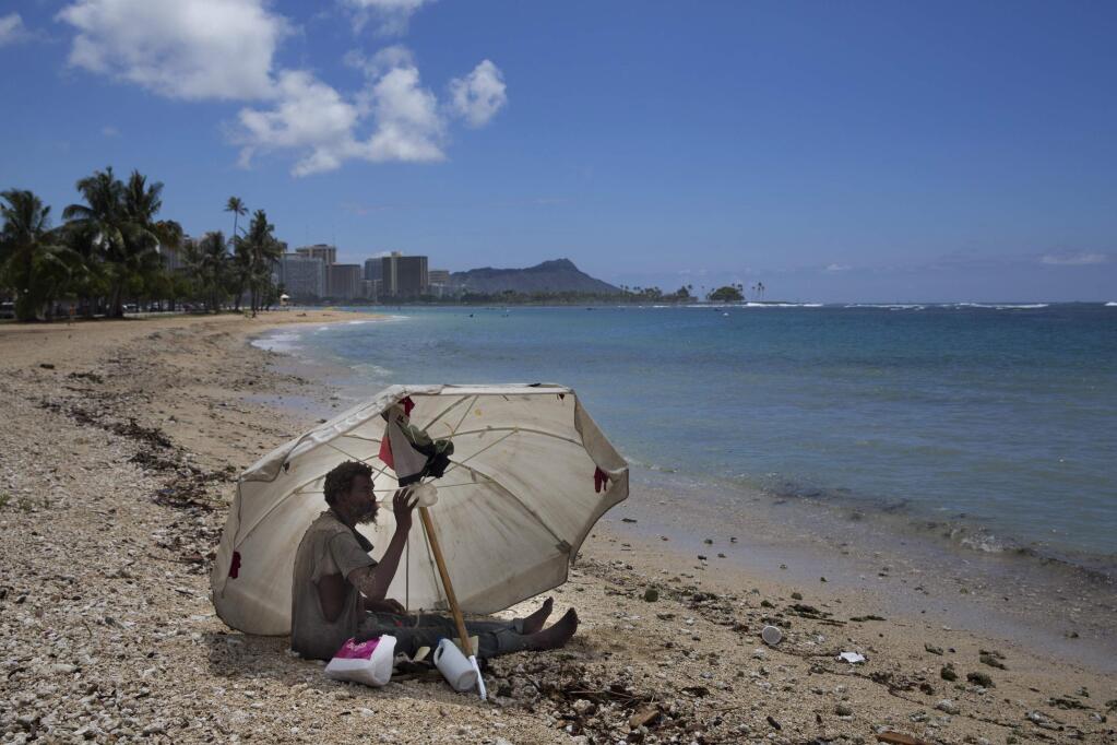 FILE - In this Aug. 27, 2015, file photo, a homeless man drinks water while sitting on the beach at Ala Moana Beach Park located near Waikiki in Honolulu. A Hawaii lawmaker wants to classify homelessness as a medical condition so that people could use Medicaid money for rent payments. As a doctor, Sen. Josh Green argues that he's constantly treating homeless people in the emergency room where he works. (AP Photo/Jae C. Hong, File)