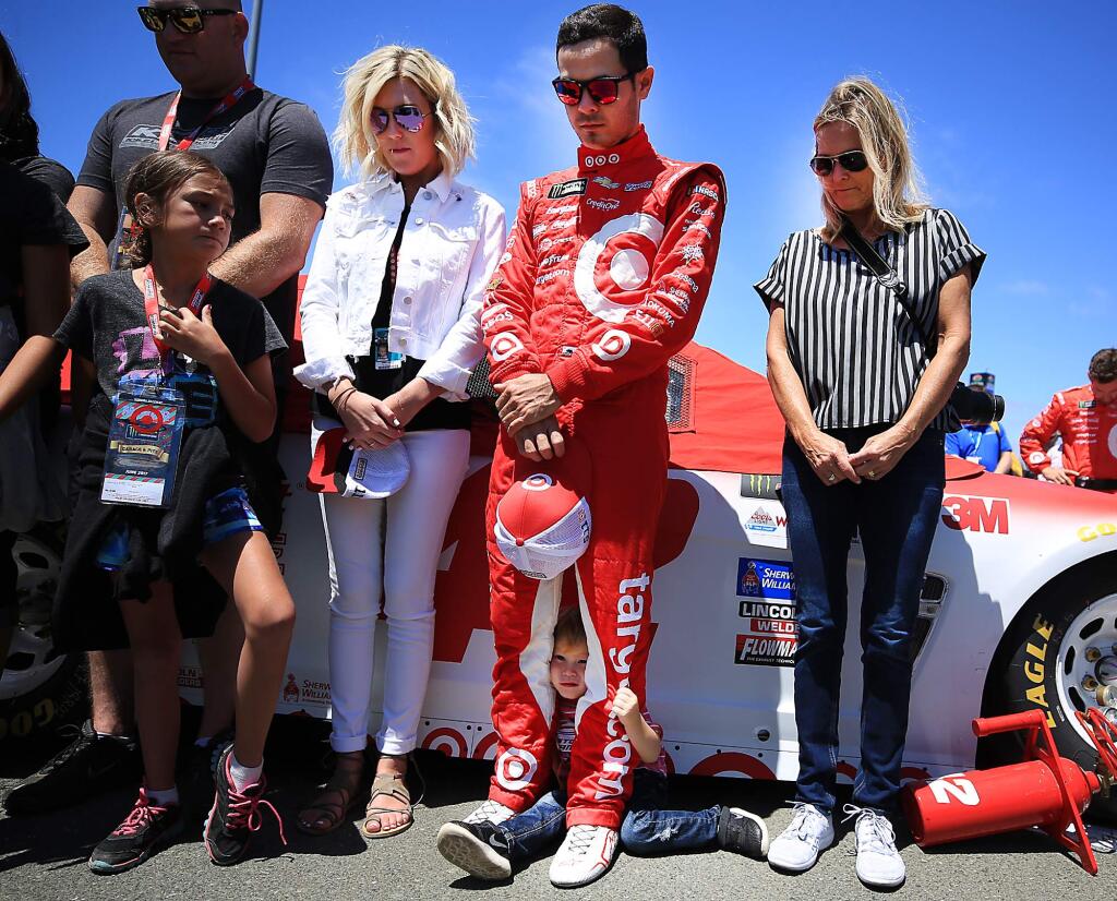 Owen Larson, 2, takes cover as his dad Kyle Larson, and mother Katelyn Sweet, left, listen to a prayer prior to the Toyota/Save Mart 350 at Sonoma Raceway in Sonoma, Sunday June 25, 2017. (Kent Porter / The Press Democrat) 2017