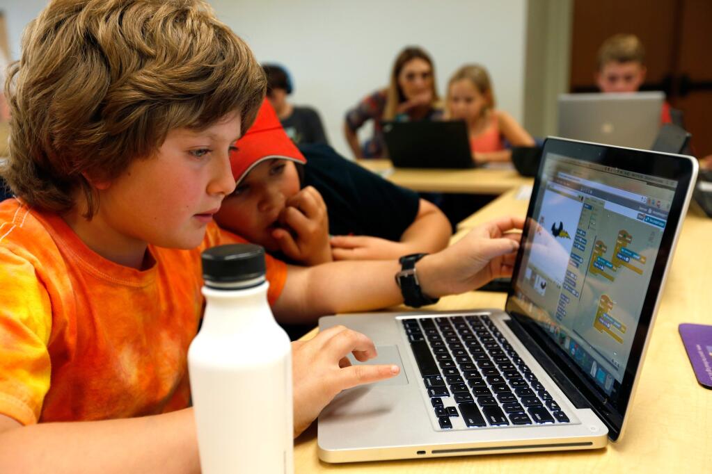 Henry LeMay, 10, left, shows Elan Sawyer, 10, how he is reprogramming computer game during Coder Dojo at the Petaluma Library in Petaluma, California on Wednesday, April 13, 2016. Coder Dojo is an international organization of community-based free computer programming clubs for young people, age 8-17. (Alvin Jornada / The Press Democrat)