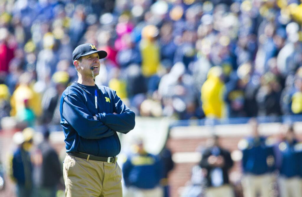Michigan head coach Jim Harbaugh stands on the field between downs during the team's Spring NCAA college football game in Ann Arbor, Mich., Saturday, April 4, 2015. (AP Photo/Tony Ding)