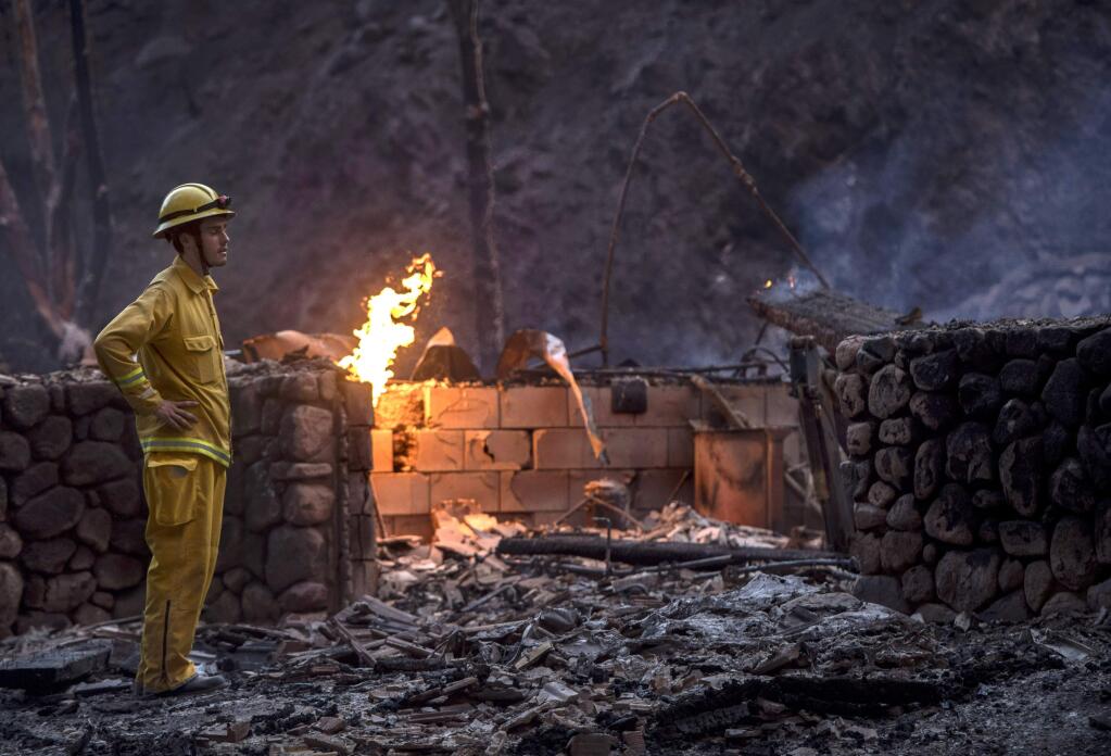 Holy Jim volunteer firefighter Luke Senger stands next to a home destroyed the Holy Fire in Trabuco Canyon, Calif., on Monday, Aug 6, 2018. (Mindy Schauer/The Orange County Register via AP)