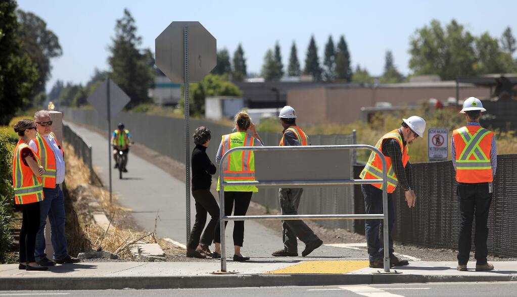 Personnel from SMART and Rohnert Park Public Works, Monday, July 1, 2019, gather on the sidewalk at Golf Course Drive and the SMART tracks, near the scene of the two deaths last Thursday and Friday of last week involving the commuter train at the intersection. (Kent Porter / The Press Democrat) 2019