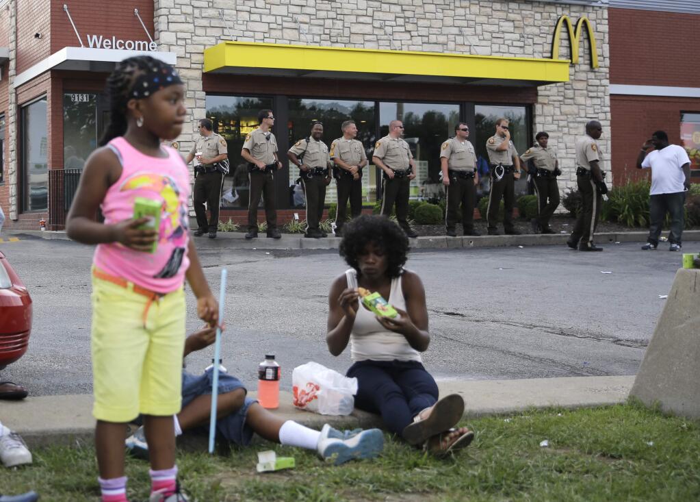 Police officers stand watch Monday, Aug. 18, 2014, in Ferguson, Mo. Missouri Gov. Jay Nixon called in the National Guard Monday after police again used tear gas to quell protesters in the wake of the shooting of Michael Brown. (AP Photo/Jeff Roberson)