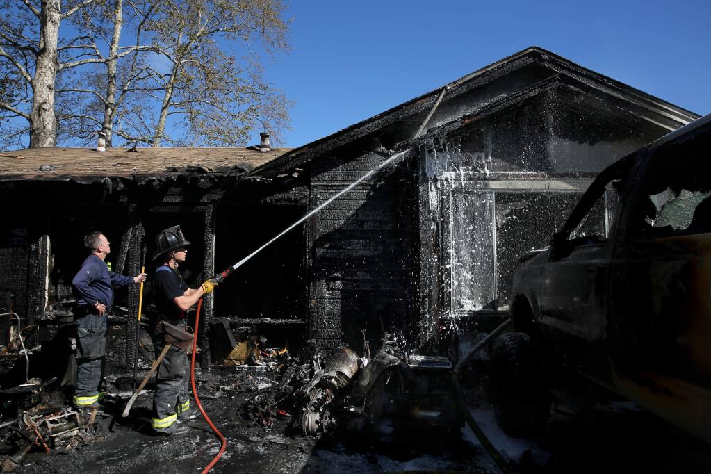 Santa Rosa Fire Captain Anthony Westergaard, left, and Engineer A.J. Alcocer try to put out a fire at 351 College Ave. in Santa Rosa on Sunday, March 31, 2019. (BETH SCHLANKER/ PD)