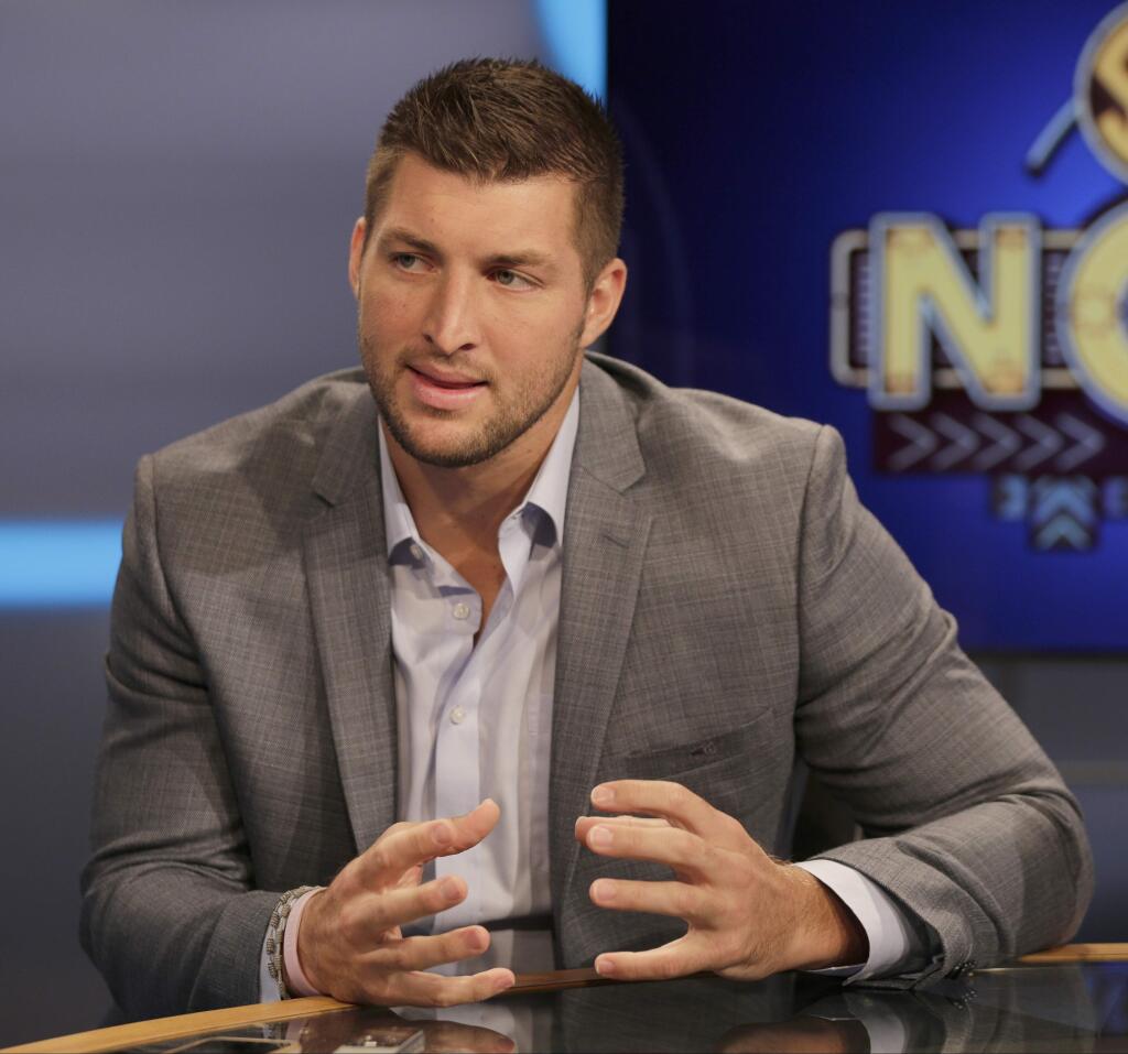 FILE - In this Aug. 6, 2014, file photo, Tim Tebow answers a question during a interview on the set of ESPN's new SEC Network in Charlotte, N.C. Tebow will be featured at the Republican National Convention in Cleveland next week. Tebow will be there. Tom Brady will pass. (AP Photo/Chuck Burton, File)