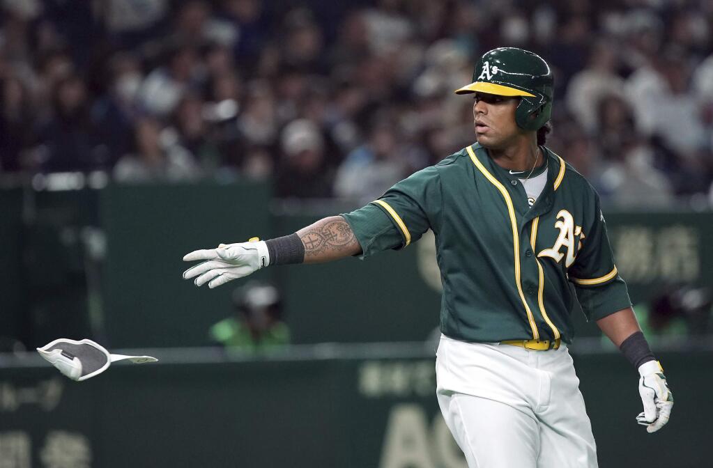 Oakland Athletics designated hitter Khris Davis throws his elbow pad as he walks to first base in the ninth inning of their pre-season exhibition baseball game against the Nippon Ham Fighters at Tokyo Dome in Tokyo Sunday, March 17, 2019. (AP Photo/Eugene Hoshiko)