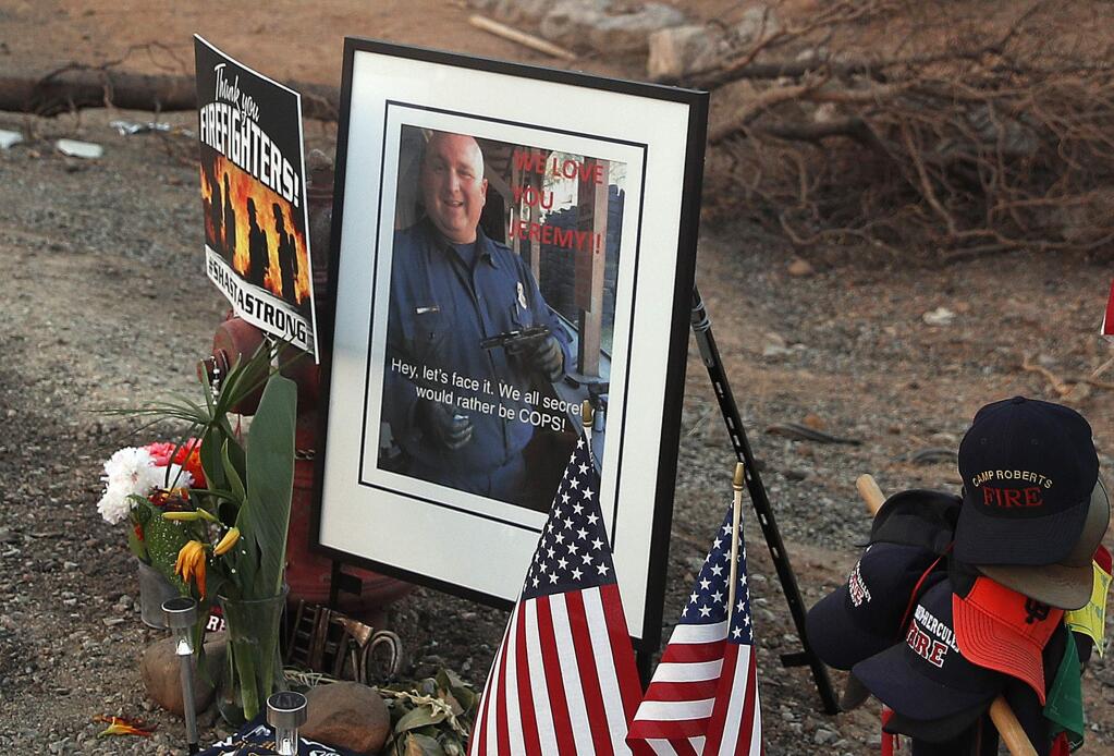 FILE - In this Aug. 11, 2018, file photo, a photo of Redding Fire Department firefighter Jeremy Stoke, who was killed in the Carr Fire, is shown at a makeshift, roadside memorial in Redding, Calif. The California Department of Forestry and Fire Protection says in a report that Redding firefighter Stoke died July 26, 2018, after he was enveloped in seconds by a fire tornado with a base the size of three football fields and winds up to 165 miles an hour. (AP Photo/John Locher, File)