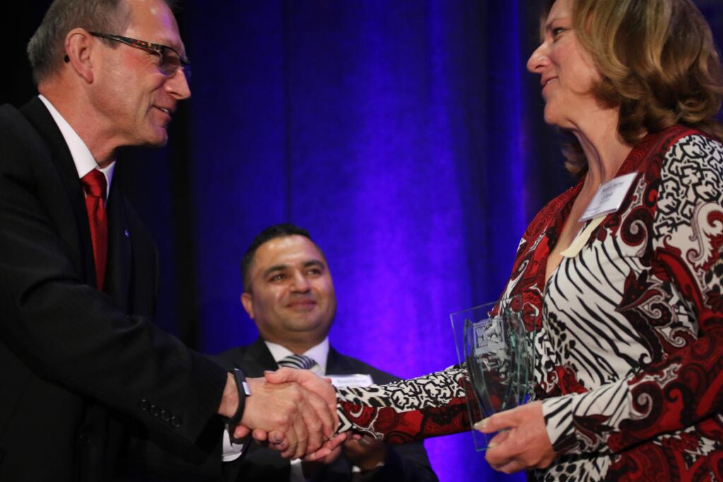 Winner Elena Whorton, president of ProTransport-1, gets a congratulatory handshake from North Bay Business Journal Publisher Brad Bollinger, with Ashoo Vaid of Wells Fargo, at Women in Business Awards, June 24, 2015, in Santa Rosa. (Jeff Quackenbush, The Business Journal)