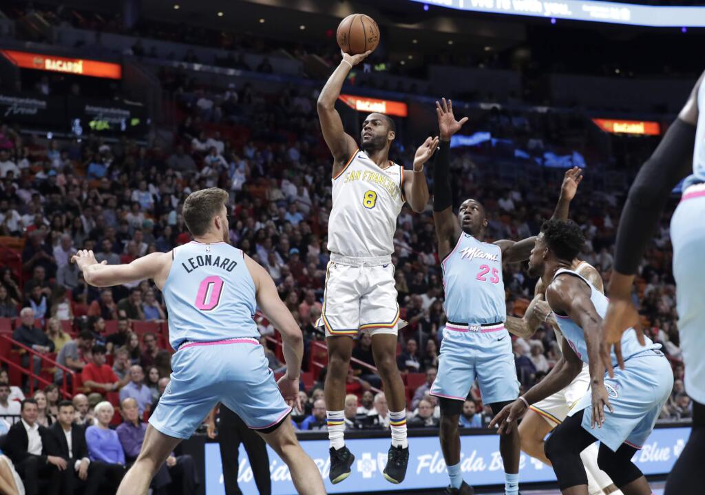 Golden State Warriors guard Alec Burks, center, shoots over Miami Heat forward Meyers Leonard (0) and guard Kendrick Nunn (25) during the first half, Friday, Nov. 29, 2019, in Miami. (AP Photo/Lynne Sladky)