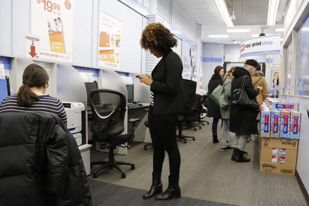 FILE - In this Tuesday, March 1, 2016, file photo, customers work in a Staples copy & print shop in New York. On Wednesday, June 28, 2017, private equity firm Sycamore announced it is buying office supplies chain Staples for $6.9 billion. (AP Photo/Mark Lennihan, File)