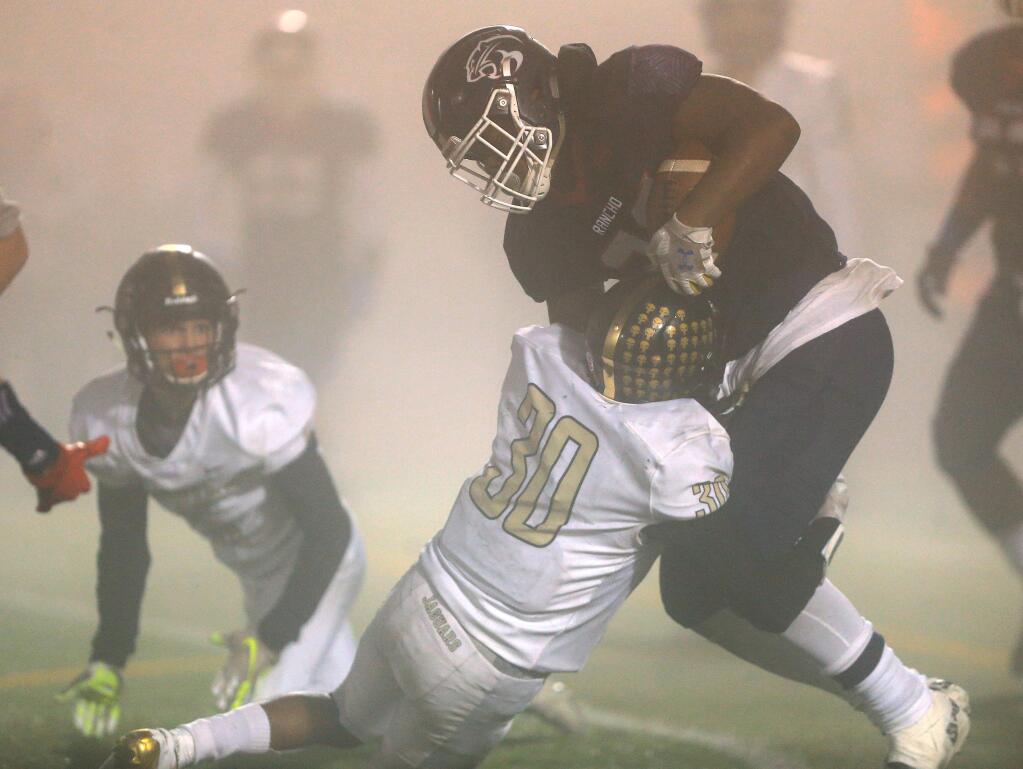 In what could be described as the fog bowl, Rasheed Rankin of Rancho Cotate plows through Windsor's EZ Woodard, Friday, Nov. 15, 2019 in Rohnert Park (Kent Porter / The Press Democrat)