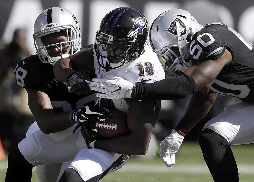 Baltimore Ravens wide receiver Jeremy Maclin is tackled by Oakland Raiders cornerback T.J. Carrie, left, and linebacker Nicholas Morrow during the first half in Oakland, Sunday, Oct. 8, 2017. (AP Photo/Marcio Jose Sanchez)