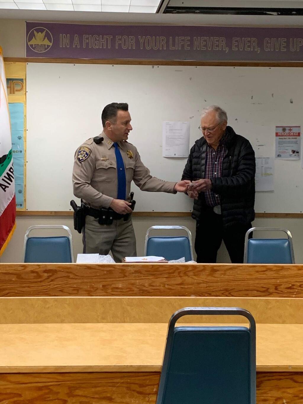 Santa Rosa CHP Commander Aristotle Wolfe presents retired CHP Officer Jim Emmons, 93, with a replacement badge at the agency's Rohnert Park office, Thursday, Feb. 23, 2020. (Nashelly Chavez/ The Press Democrat)