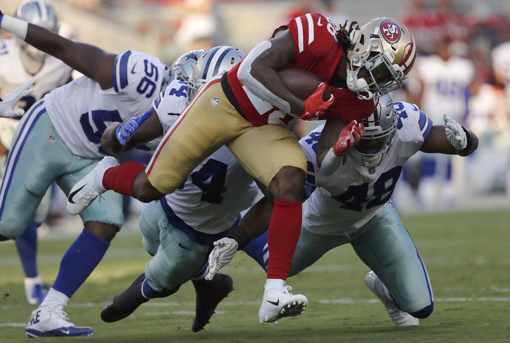 In this Aug. 9, 2018, file photo, San Francisco 49ers running back Jerick McKinnon, foreground, carries against Dallas Cowboys defensive end Datone Jones (56), linebacker Jaylon Smith, center left, and linebacker Joe Thomas (48) during the first half in Santa Clara. (AP Photo/Josie Lepe, File)