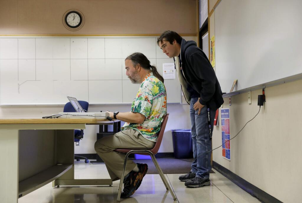 Donald Laird, Chair of Computer Studies Dept., and his son, Sutter, retouch a image that was found partially burned during the recent wildfires. Photo taken in his classroom at the Santa Rosa Junior College in Santa Rosa, on Sunday, October 29, 2017. (BETH SCHLANKER/ The Press Democrat)