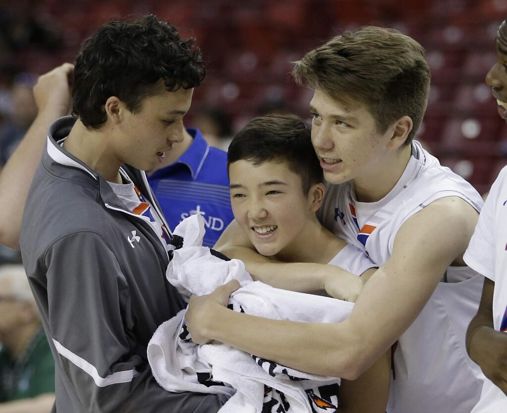 Freshman guard Kobe Keiner, center, of St. Joseph of Notre Dame, is hugged by teammates Cameron Ba, left, and Thomas Nilson after making two free throws in the closing moments against St. Bernard, in the Boys Division V High School Basketball Championship game Thursday, March 24, 2016, in Sacramento, Calif. St. Joseph won 55-50. (AP Photo/Rich Pedroncelli)