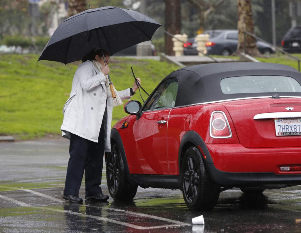 Em Sarikaya checks her the wipers blades on her car as rain falls in Los Angeles. Friday, Dec. 20, 2017. The second in a trio of storms has arrived in California. Rain, heavy at times, is overspreading the state early Friday and a flash flood warning has been issued for southeastern Sonoma County. Storm warnings are posted up and down the Sierra Nevada and across the mountains of Southern California. (AP Photo/Damian Dovarganes)