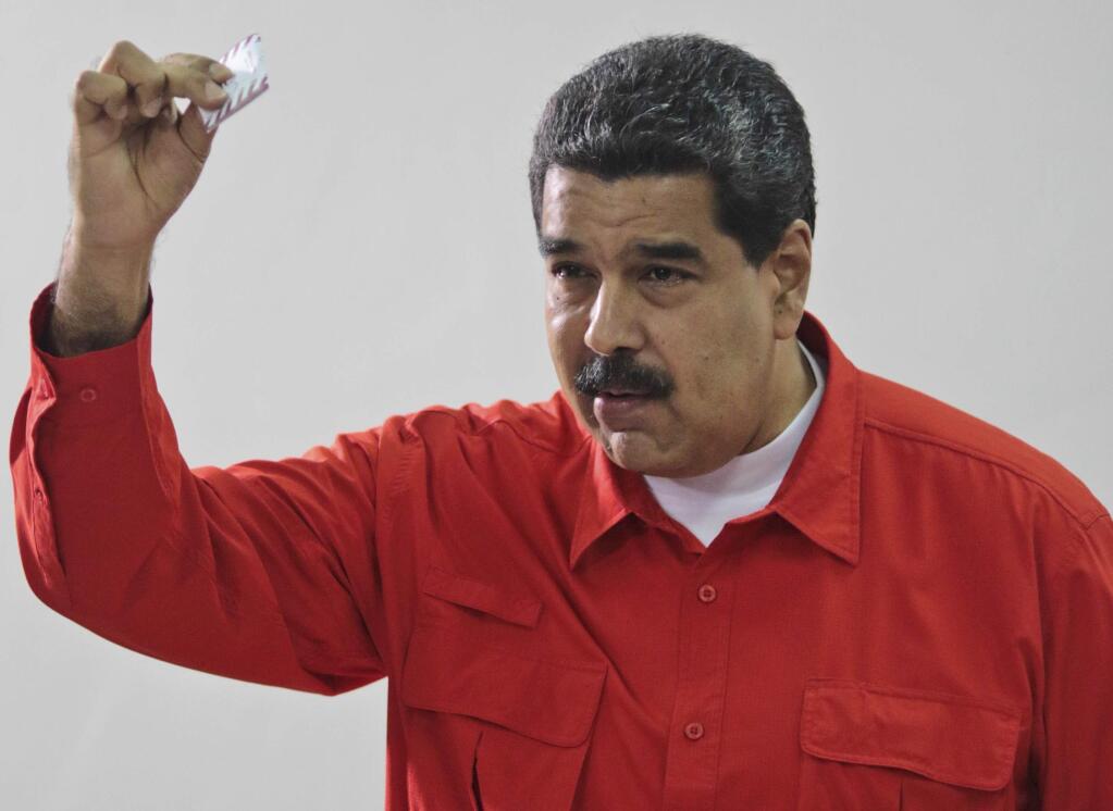 In this photo released by Miraflores Press Office, Venezuela's President Nicolas Maduro shows his ballot after casting a vote for a constitutional assembly in Caracas, Venezuela on Sunday, July 30, 2017. Maduro asked for global acceptance on Sunday as he cast an unusual pre-dawn vote for an all-powerful constitutional assembly that his opponents fear he'll use to replace Venezuelan democracy with a single-party authoritarian system. (Miraflores Press Office via AP)