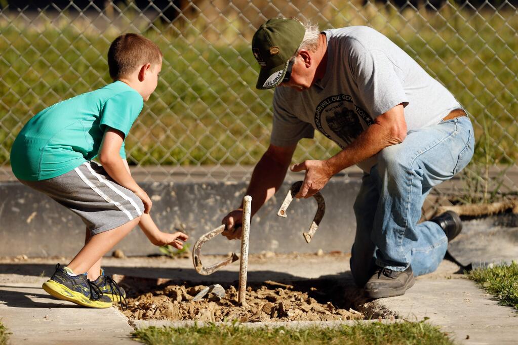 Connor Hawkins, 9, left, and his grandfather Carmen Cavallero retrieve their horseshoes from the clay pit surrounding the stake during their game at the Sonoma County Horseshoe Pitchers' Club at Doyle Park in Santa Rosa, California on Tuesday, June 14, 2016. (Alvin Jornada / The Press Democrat)
