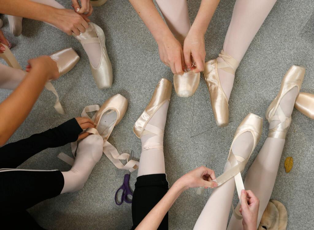 Ballet dancers lace the ribbons on their pointe shoes before a dress rehearsal for Santa Rosa Dance Theater's annual production of The Nutcracker ballet at Spreckels Performing Arts Center in Rohnert Park, California on Thursday, December 15, 2016. (Alvin Jornada / The Press Democrat)