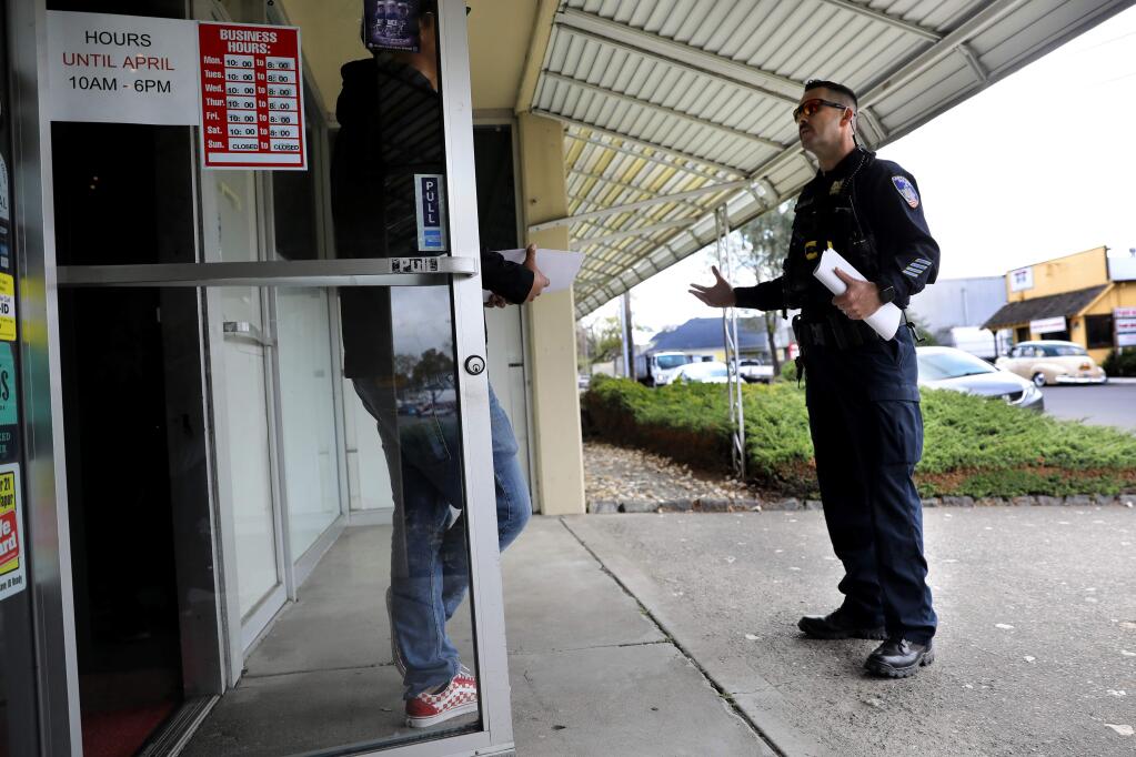 Santa Rosa Police Officer Armando Jauregui talks with the owner of Smoke and Mirrors Vapor Lounge to make sure they are complying with the shelter-in-place order. Photo takeb in Santa Rosa on Tuesday, March 31, 2020. (BETH SCHLANKER/ The Press Democrat)