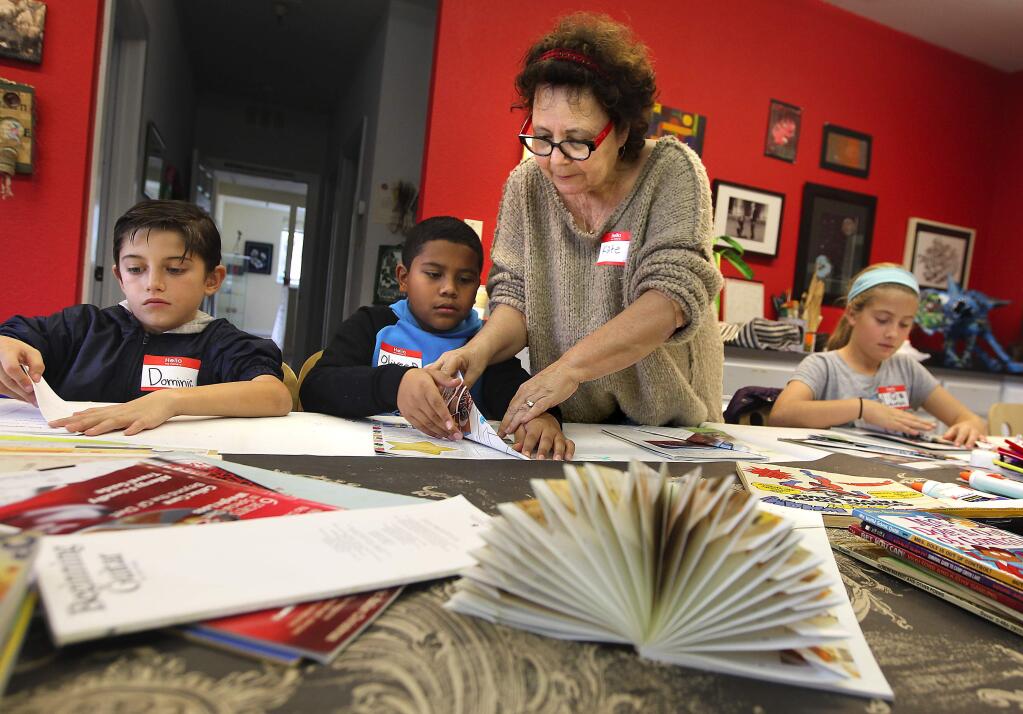 Artist Kate Ortulano makes Christmas trees out of magazines with Flowery School students Dominic Contreras, left, Oliver Dorantes and Lauren Johnston on at Artescape in Sonoma. (Photo by John Burgess/The Press Democrat)