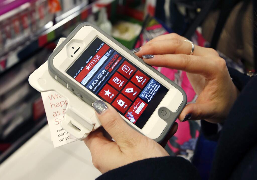 FILE - In this Friday, Nov. 23, 2012, file photo, Tashalee Rodriguez, of Boston, uses a smartphone app while shopping at Macy's in downtown Boston. Shoppers are flocking online Monday, Nov. 28, 2016, as “Cyber Monday” sales hit their peak. Each year, during the busy holiday shopping weekend that kicks off on Thanksgiving and the Friday after, known as Black Friday, more and more shoppers decide to skip the mayhem in stores and shop online. (AP Photo/Michael Dwyer, File)