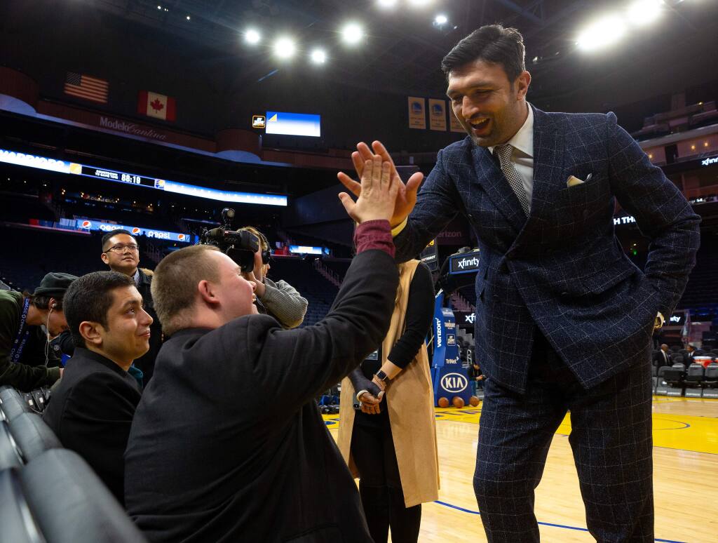 Basketball executive and former Golden State Warriors player Zaza Pachulia high-fives Austin Roach after chatting with him and Mauricio Stillman, far left, while they watch pregame warm ups a basketball game between the Indiana Pacers and Golden State Warriors at the Chase Center in San Francisco, California, on Friday, January 24, 2020. (Alvin Jornada / The Press Democrat)