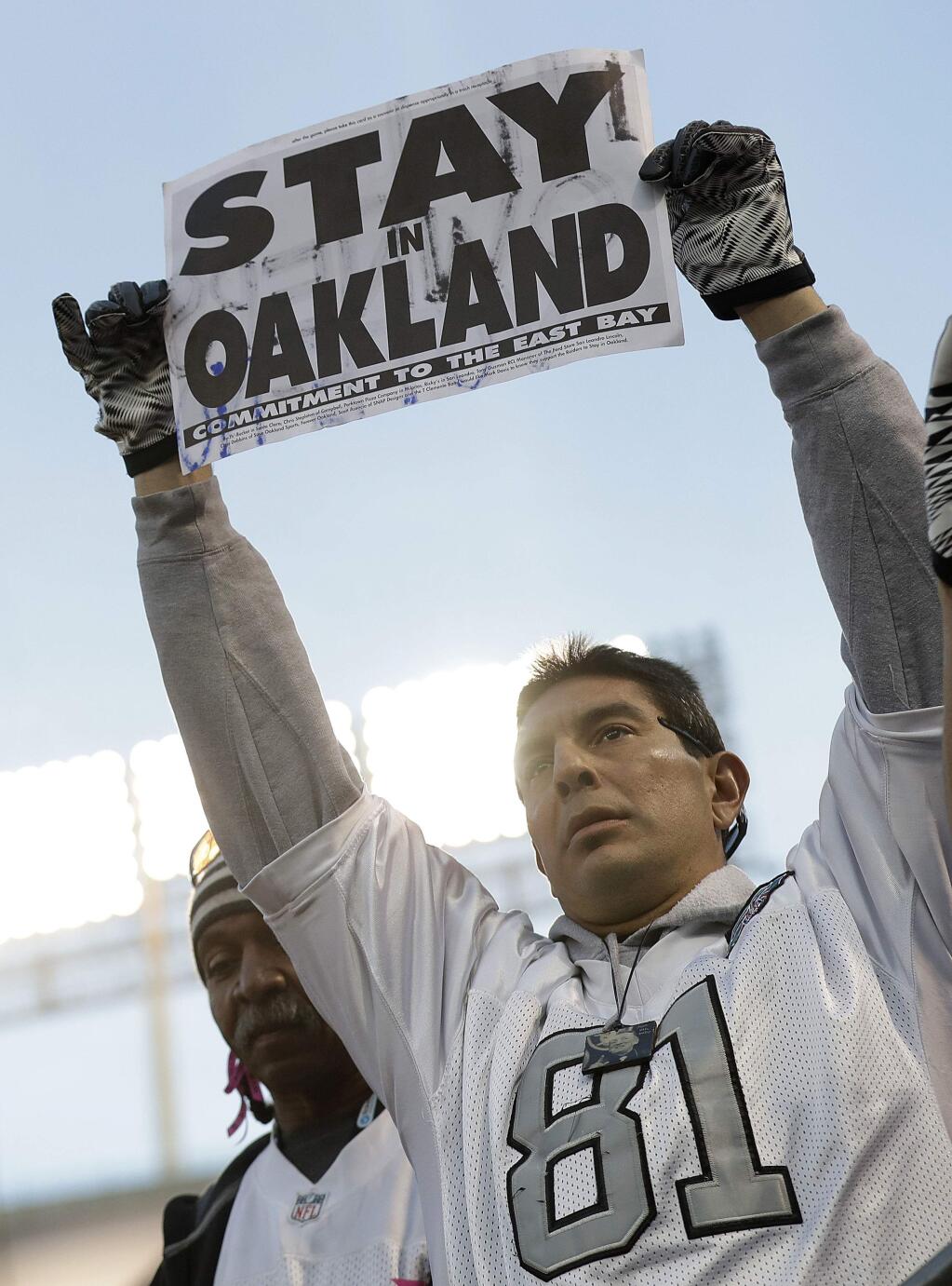 An Oakland Raiders fan holds up a sign about the team's possible move during the second half of a game between the Oakland Raiders and the Carolina Panthers in Oakland, Sunday, Nov. 27, 2016. The Raiders won 35-32. (AP Photo/Marcio Jose Sanchez)