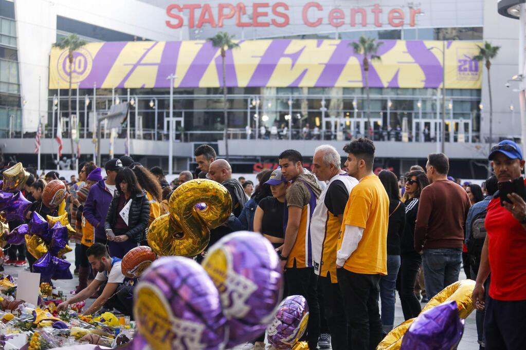 FILE - In this Jan. 31, 2020, file photo, fans gather to pay their respects at a memorial for Kobe Bryant in front of Staples Center, prior to an NBA game between the Los Angeles Lakers and the Portland Trail Blazers in Los Angeles. A person with knowledge of the details says a public memorial service for Bryant, his daughter and seven others killed in a helicopter crash is planned for Feb. 24 at Staples Center. The Los Angeles arena is where Bryant starred for the Lakers for most of his two-decade career. The date corresponds with the jersey numbers he and 13-year-old daughter Gianna wore, 24 for him and 2 for her. (AP Photo/Ringo H.W. Chiu, File)