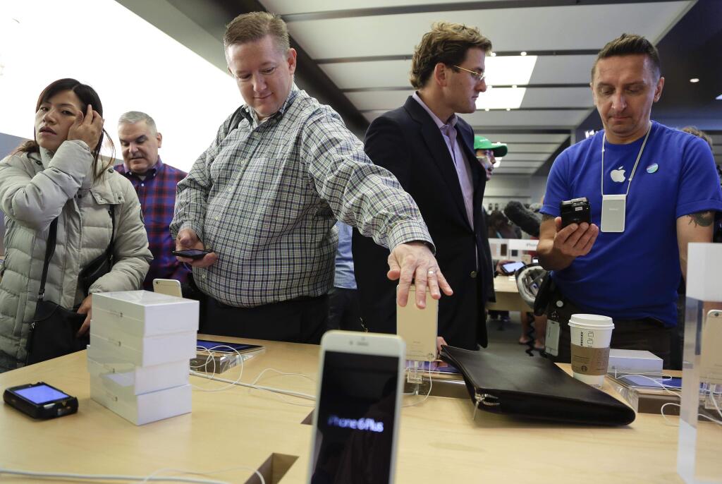 Visitors to the Apple store examine the iPhone 6 and 6 Plus, Friday, Sept. 19, 2014, in New York. The highly anticipated iPhone 6 and iPhone 6 Plus are being released in stores today. (AP Photo/Julie Jacobson)