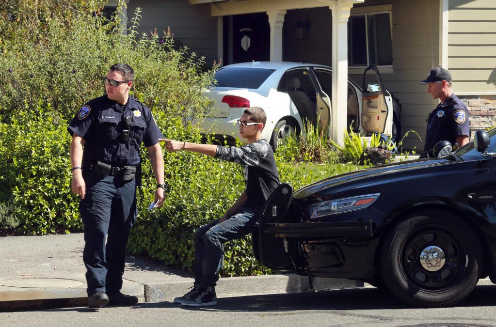 Santa Rosa Police officers interview a young driver who crashed through two front gardens on Calaveras Dr. in Santa Rosa before ramming through the wall of a garage on Thursday afternoon. (photo by John Burgess/The Press Democrat)