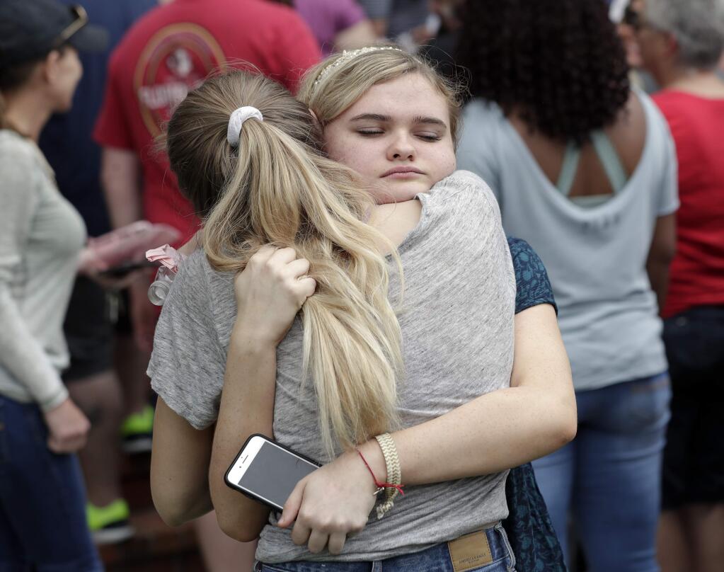 Students hug outside a staging area at the First Baptist Church of Ocala as parents arrive to pick them up after a shooting incident at nearby Forest High School, Friday, April 20, 2018, in Ocala, Fla. (AP Photo/John Raoux)