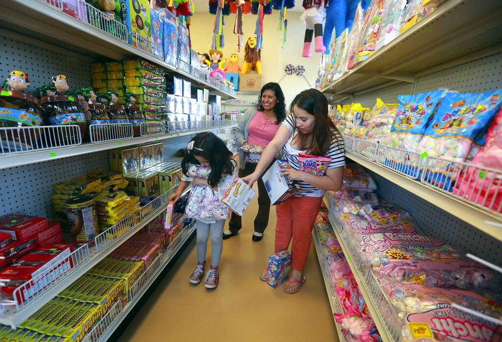 Monserrat Vargas, 7, collects bags of candy for her birthday pinata with her mother Azusena Chaparro, right, and Elva Alguilar at the Dulceria Las Tapatias in Santa Rosa. (Photo by John Burgess/The Press Democrat)