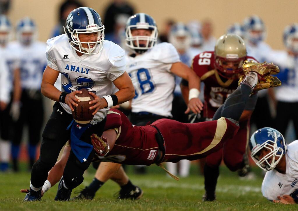 Analy quarterback Jack Newman (12) narrowly avoids a diving tackle by Cardinal Newman's Dino Kahaulelio during the first half of a game between Analy and Cardinal Newman high schools, in Santa Rosa on Friday, September 9, 2016. (Alvin Jornada / The Press Democrat)