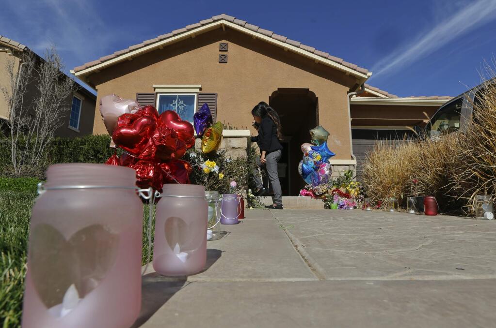 Neighbors write down messages for the Turpin's children on the front door of the home of David and Louise Turpin where police arrested the couple accused of holding 13 children captive in Perris, Calif., Wednesday, Jan. 24, 2018. The Turpin's accused of abusing their 13 children, ranging from 2 to 29, before they were rescued on Jan. 14 from their home in Perris. They have pleaded not guilty to torture and other charges. A judge signed a protective order Wednesday prohibiting the couple from contacting their children, except through attorneys or investigators. (AP Photo/Damian Dovarganes)