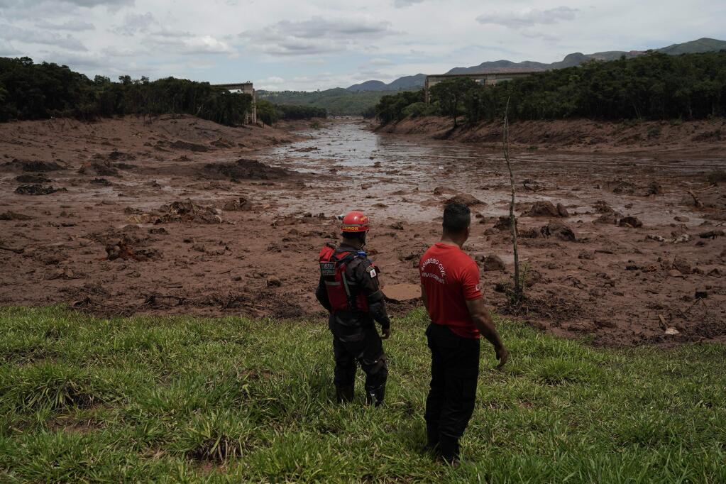 Civil firefighters survey a destroyed rail bridge two days after a dam collapse in Brumadinho, Brazil, Sunday, Jan. 27, 2019. Brazilian officials on Sunday suspended the search for potential survivors of a dam collapse that has killed at least 40 people amid fears that another nearby dam owned by the same company was also at risk of breaching. (AP Photo/Leo Correa)