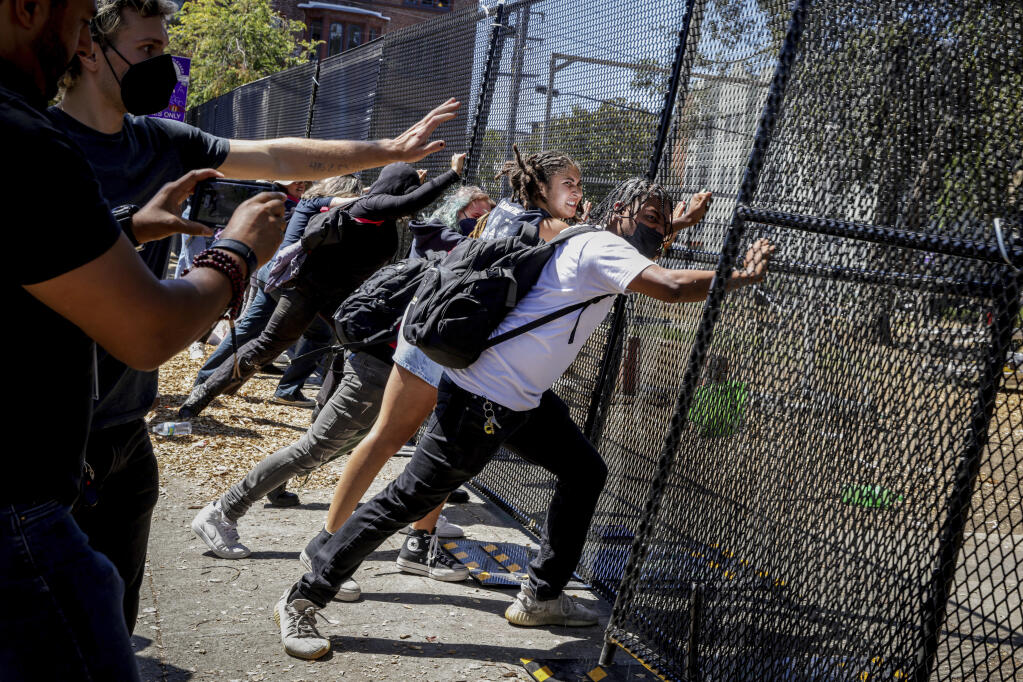 FILE - Protesters attempt to push down a fence surrounding People's Park in Berkeley, Calif. on Aug. 3, 2022. The three-acre site's colorful history, forged from University of California, Berkeley's seizure of the land in 1968, has been thrust back into the spotlight by the school's renewed effort to pave over People's Park as part of a $312 million project that includes sorely needed housing for about 1,000 students. (Brontë Wittpenn/San Francisco Chronicle via AP, File)