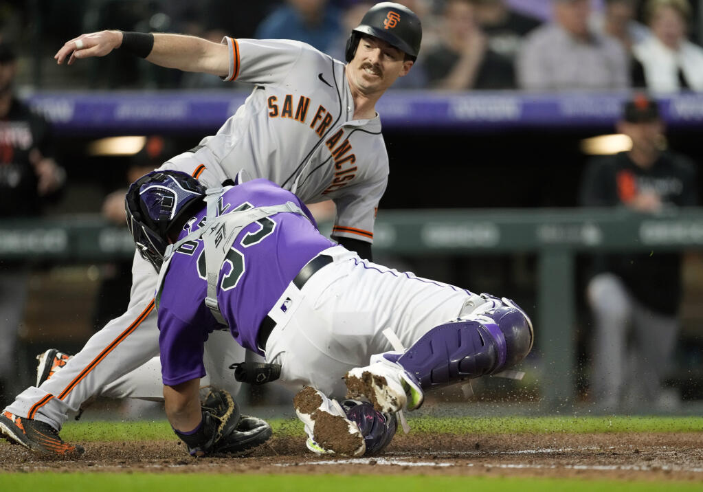 The San Francisco Giants’ Mike Yastrzemski, back, slides safely into home plate to score on a double hit by Darin Ruf as Colorado Rockies catcher Elias Diaz turns to apply a late tag in the fourth inning on Tuesday, May 17, 2022, in Denver. (David Zalubowski / ASSOCIATED PRESS)