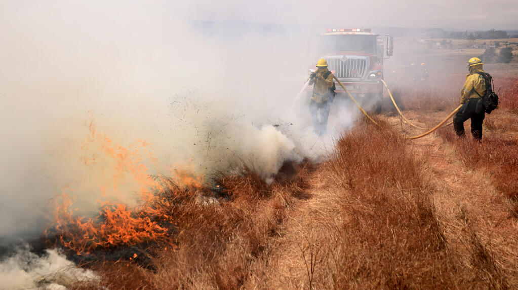 Marin County Cal Fire firefighters put flames out with a mobile attack during the Middle fire, Friday, Aug. 13, 2021 on Middle Two Rock road west of Petaluma.  (Kent Porter / The Press Democrat)