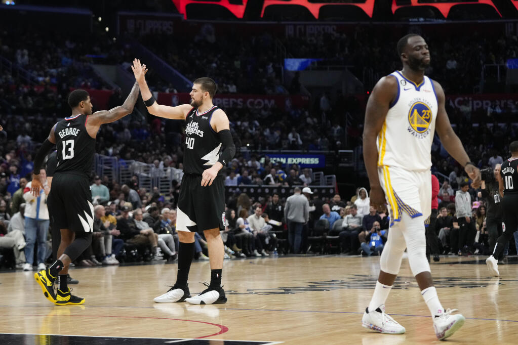 The Clippers’ Paul George, left, celebrates his 3-point basket with Ivica Zubac as the Warriors’ Draymond Green walks to the bench for a timeout during the second half Wednesday in Los Angeles. The Clippers won 134-126. (Jae C. Hong / ASSOCIATED PRESS)